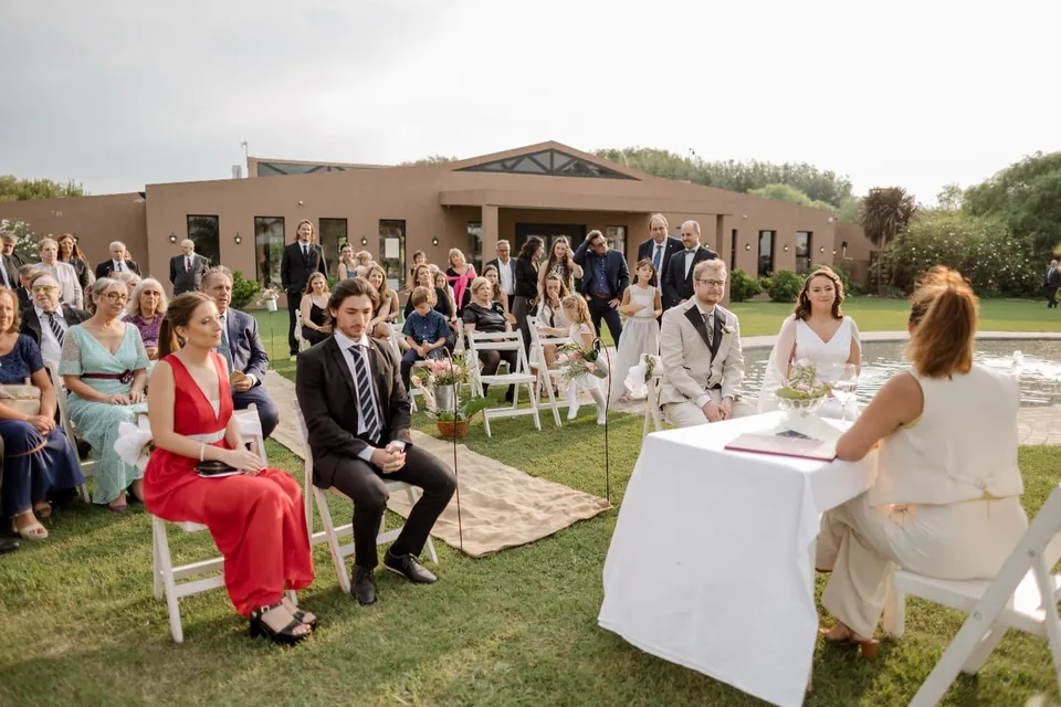 Pareja e invitados durante una ceremonia en el jardín, frente al salón