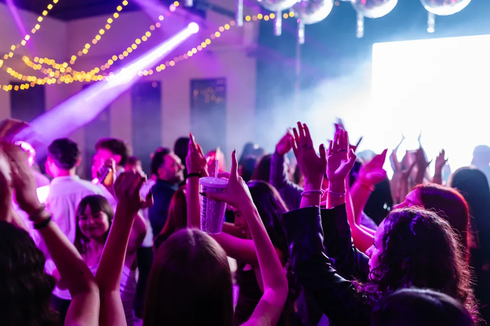 Invitados bailando con las manos levantadas durante una fiesta de quince