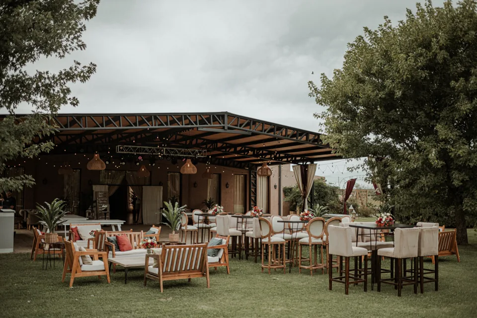 Galería cubierta abierta al jardín con livings y mesas para una recepción