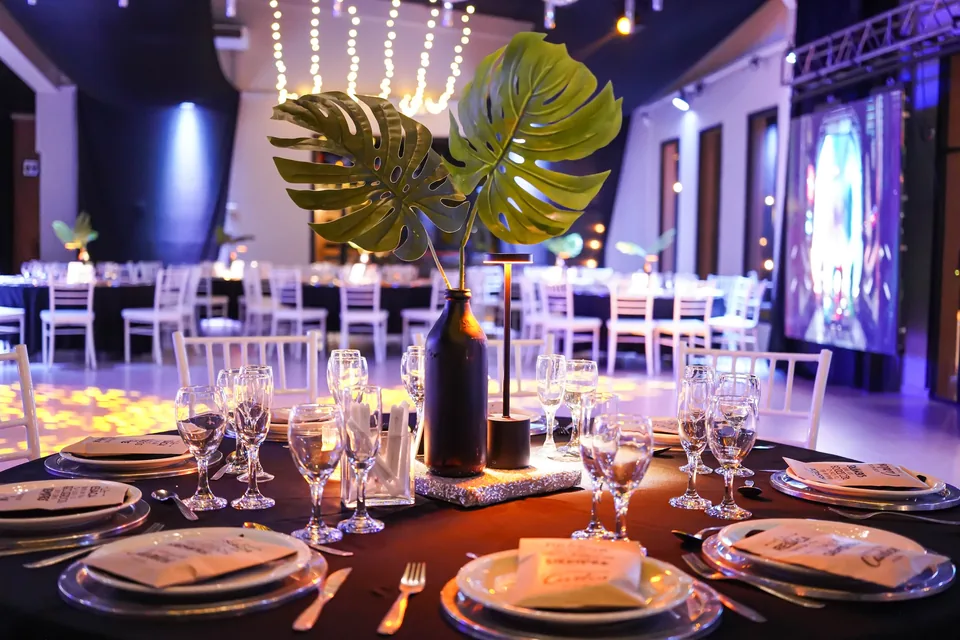 Mesa preparada para un cumpleaños con copas, velas y hojas verdes