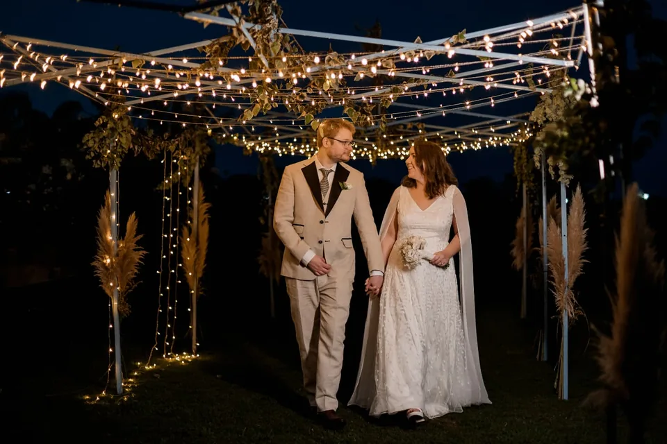 Pareja bajo guirnaldas de luces en el jardín de noche