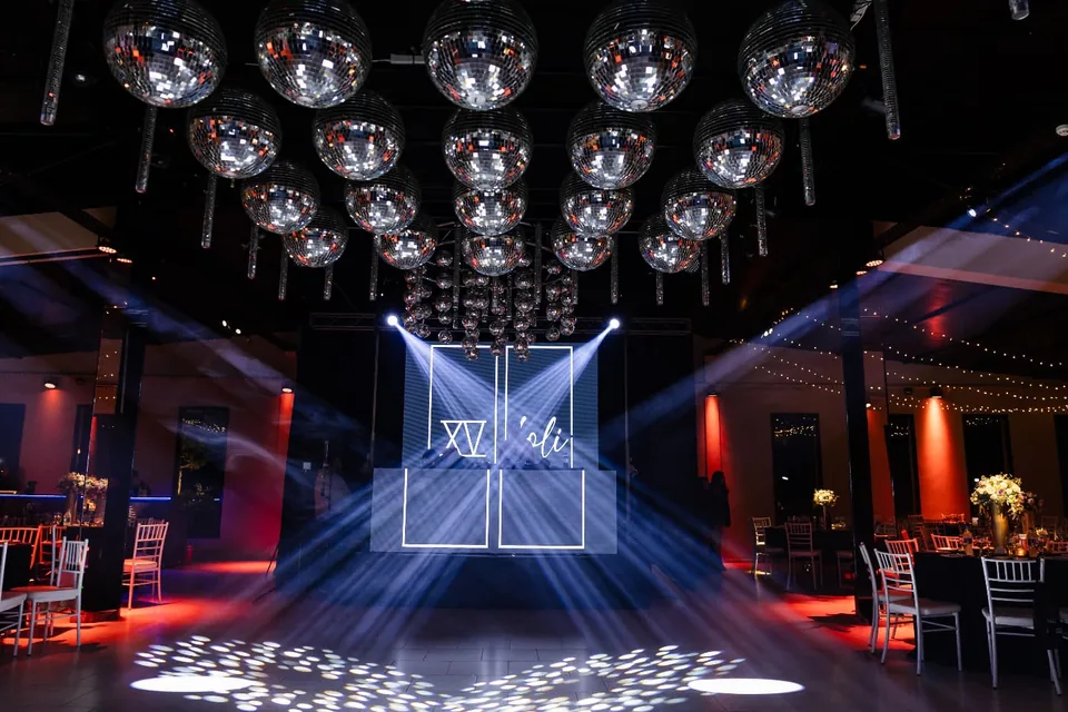 Pista iluminada con haces de luz y pantallas LED durante una fiesta de quince