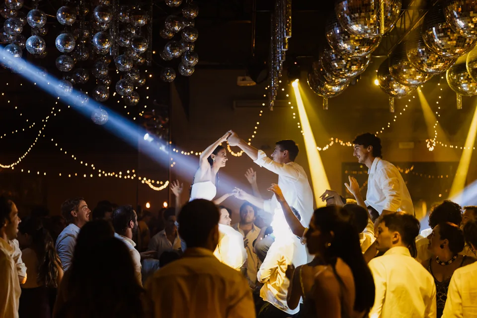 Pista de baile con invitados, esferas y haces de luz cálida
