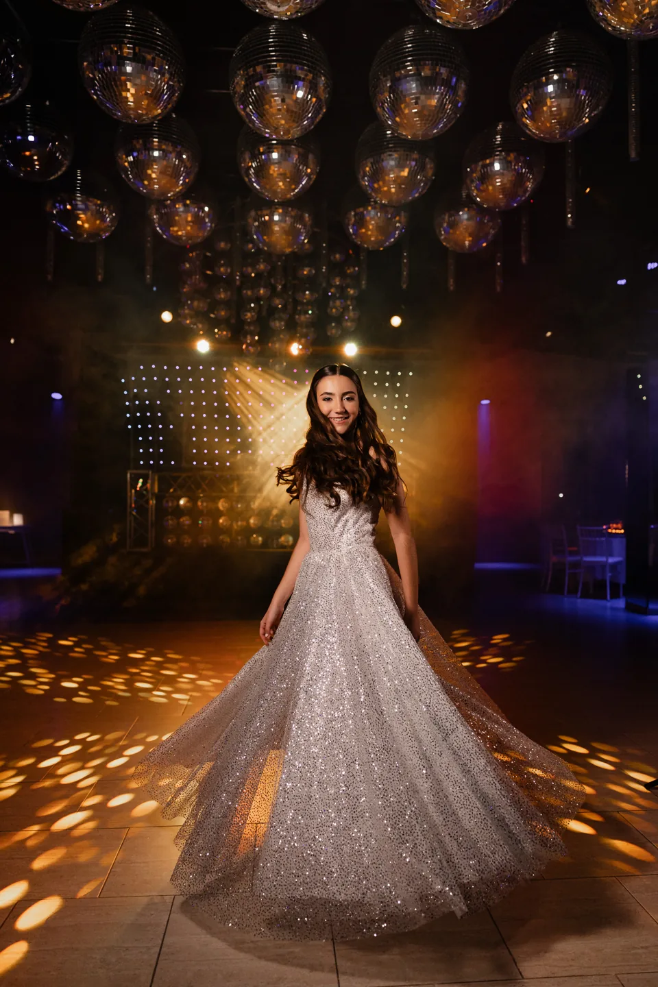 Quinceañera en la pista bajo las esferas del salón