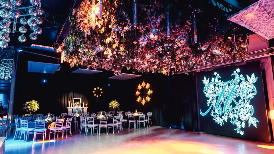 Salón con ambientación floral suspendida y pantalla LED para una fiesta de quince