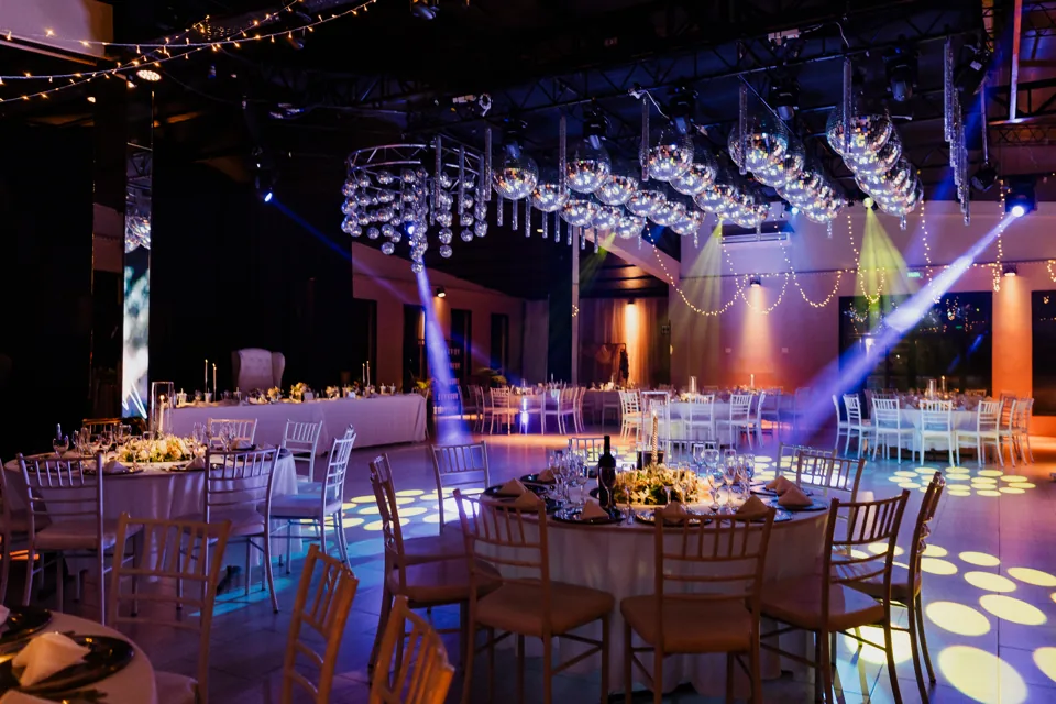 Salón preparado para quince años con mesas, esferas y luces violetas